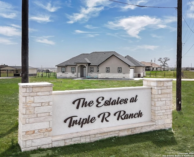 community / neighborhood sign featuring a lawn, driveway, and fence