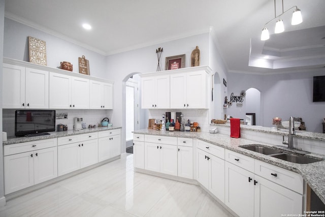 kitchen with white cabinets, arched walkways, ornamental molding, and a sink