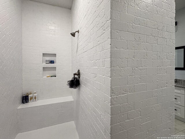 bathroom with a tile shower and vanity