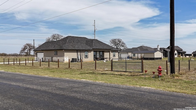 view of front of home with a gate, fence, central AC unit, a garage, and a front yard