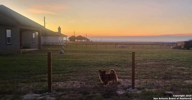 yard at dusk with fence and a rural view