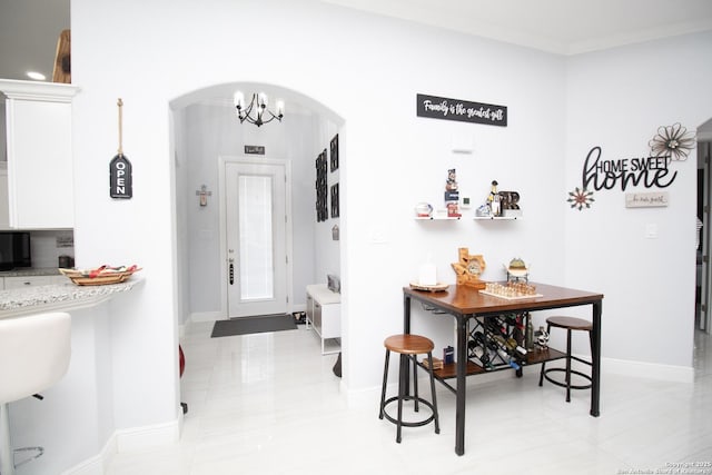 interior space featuring ornamental molding, arched walkways, baseboards, and a chandelier