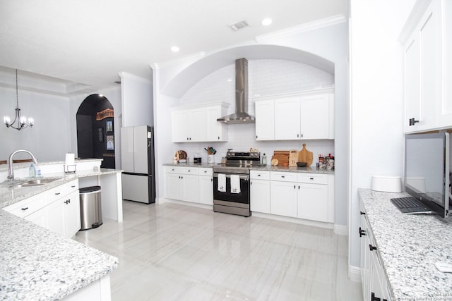 kitchen with electric range, a sink, freestanding refrigerator, a notable chandelier, and wall chimney exhaust hood