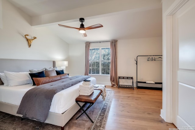 bedroom with a ceiling fan, wood finished floors, and vaulted ceiling with beams
