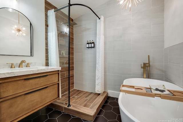 full bath featuring tile patterned floors, vanity, tiled shower, and tile walls