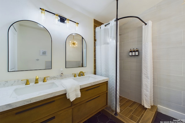 bathroom featuring double vanity, wood finish floors, a tile shower, and a sink
