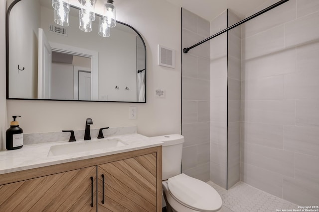bathroom with vanity, toilet, visible vents, and tiled shower