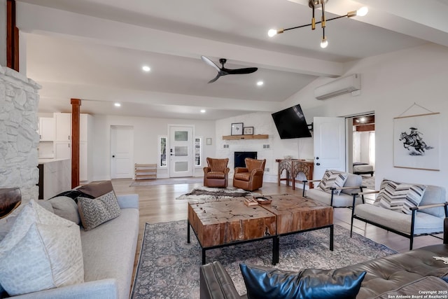 living room with a wall mounted air conditioner, ceiling fan with notable chandelier, a large fireplace, light wood-style floors, and vaulted ceiling with beams