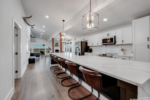 kitchen with vaulted ceiling, white cabinets, a notable chandelier, and stainless steel appliances
