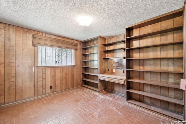 10103 Northampton, San Antonio, TX 78230 - unfurnished office featuring brick patterned floors, wood walls, a textured ceiling, built in desk, and baseboards