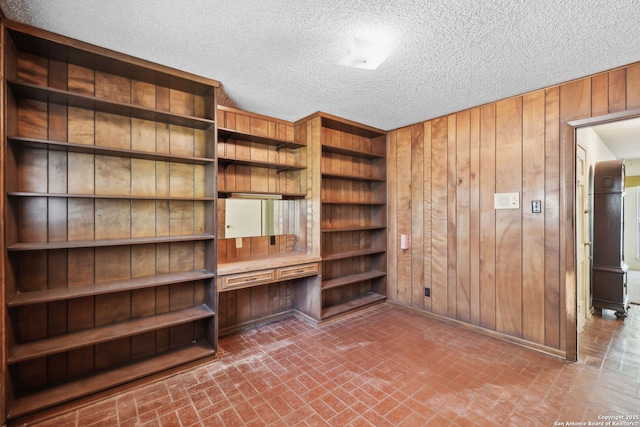 10103 Northampton, San Antonio, TX 78230 - unfurnished room featuring brick patterned flooring, wood walls, a textured ceiling, an office area, and baseboards