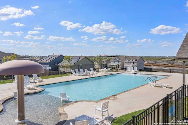 community pool featuring a residential view, a patio area, and fence
