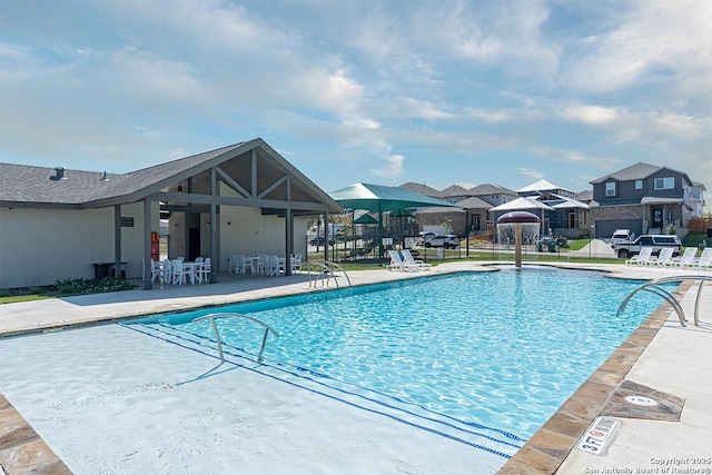 pool with a patio area and fence