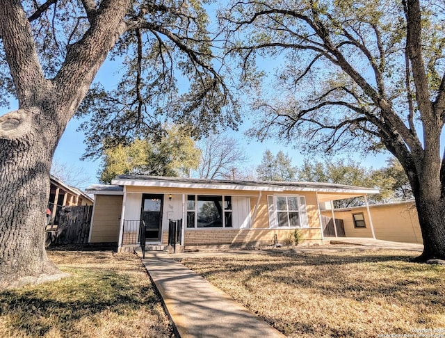 single story home featuring a front yard, a carport, and board and batten siding