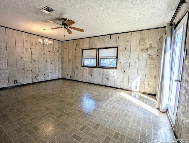 spare room with visible vents, brick patterned floor, a textured ceiling, and ceiling fan with notable chandelier