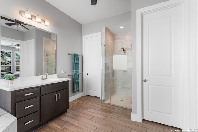 full bathroom featuring vanity, wood finished floors, baseboards, a stall shower, and ceiling fan