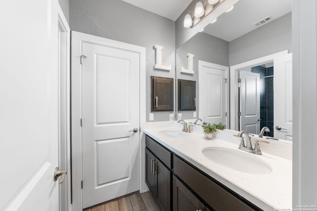 bathroom with double vanity, wood finished floors, visible vents, and a sink