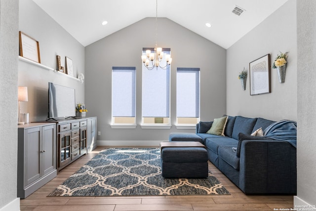 living area with light wood finished floors, visible vents, baseboards, lofted ceiling, and an inviting chandelier