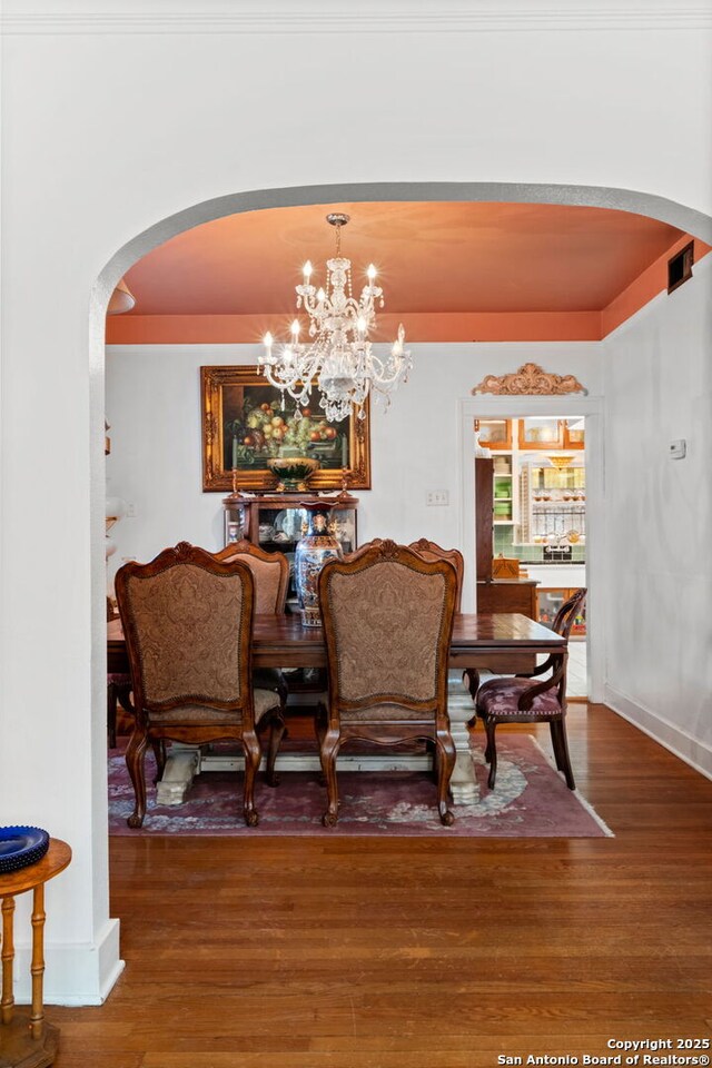243 E Lullwood, San Antonio, TX 78212 - dining room featuring visible vents, arched walkways, an inviting chandelier, and wood finished floors