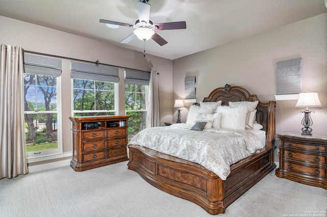 bedroom featuring light colored carpet, a ceiling fan, and multiple windows
