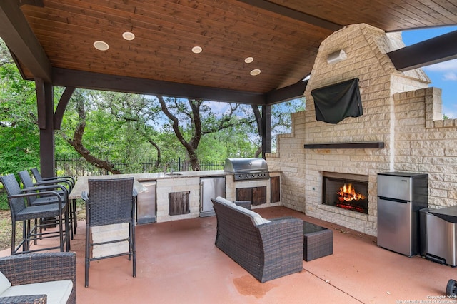 view of patio featuring a sink, an outdoor brick fireplace, a bar, area for grilling, and exterior kitchen