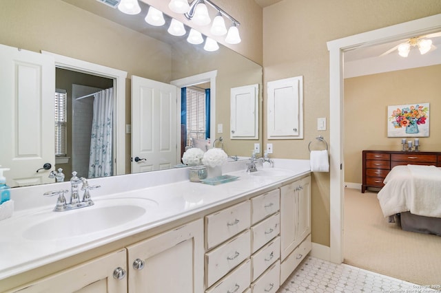ensuite bathroom with double vanity, a sink, connected bathroom, and baseboards
