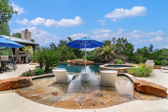 outdoor pool featuring an in ground hot tub and a patio area