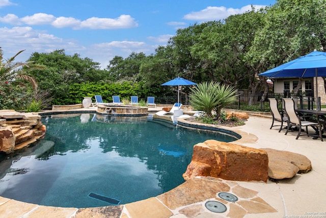 view of swimming pool with a patio, a pool with connected hot tub, and fence