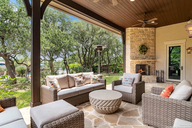 view of patio with ceiling fan, an outdoor living space with a fireplace, and a fenced backyard