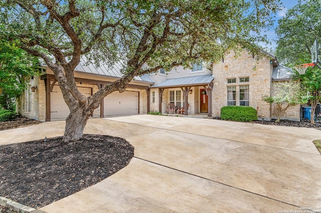 traditional-style home with a standing seam roof, metal roof, stone siding, concrete driveway, and an attached garage