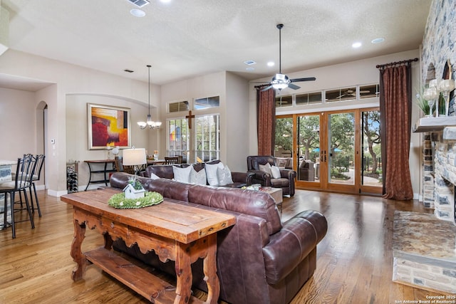 living area with recessed lighting, arched walkways, ceiling fan with notable chandelier, and light wood-style floors