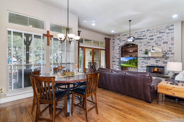 dining space featuring hardwood / wood-style flooring, visible vents, recessed lighting, a fireplace, and ceiling fan with notable chandelier