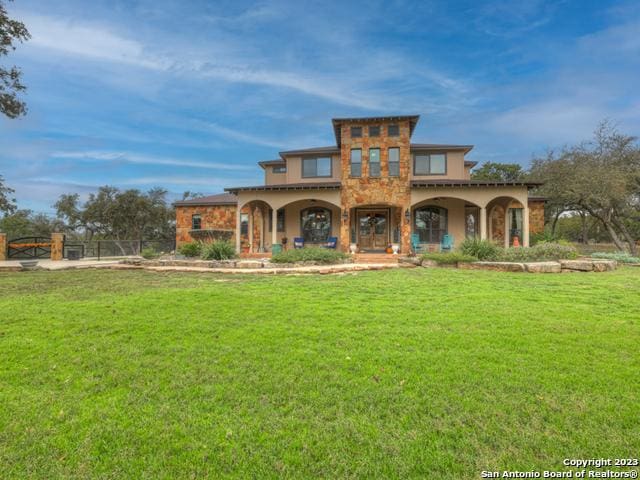 1236 Primrose Path, Canyon Lake, TX 78133 - mediterranean / spanish-style home featuring a front lawn, fence, stone siding, and stucco siding
