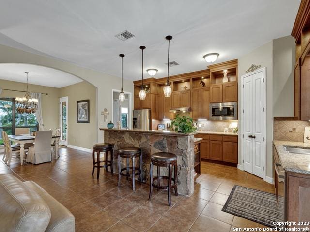 1236 Primrose Path, Canyon Lake, TX 78133 - kitchen featuring visible vents, brown cabinets, arched walkways, stainless steel appliances, and a sink