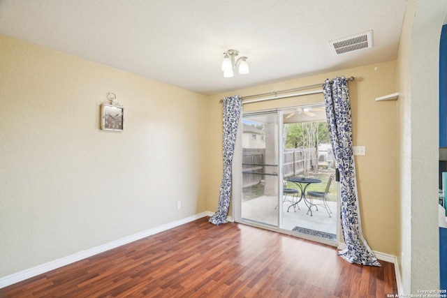 spare room featuring visible vents, baseboards, and wood finished floors
