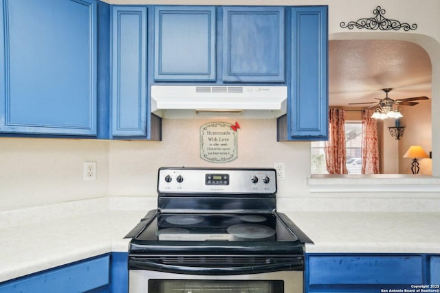 kitchen featuring stainless steel electric range, light countertops, blue cabinets, and under cabinet range hood