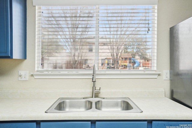 kitchen featuring light countertops, a sink, and blue cabinetry