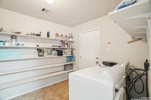 laundry room featuring visible vents, stone finish floor, washing machine and dryer, and laundry area