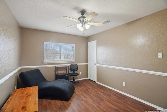 sitting room with wood finished floors, a textured wall, and visible vents