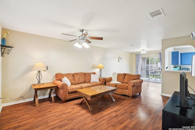 living area featuring visible vents, ceiling fan, baseboards, and wood finished floors