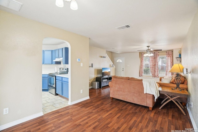 living room featuring arched walkways, wood finished floors, ceiling fan, and visible vents