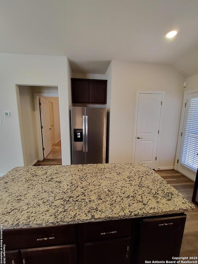 1976 Cowan Dr, New Braunfels, TX 78132 - kitchen featuring a kitchen island, light stone countertops, dark brown cabinetry, stainless steel fridge with ice dispenser, and wood finished floors