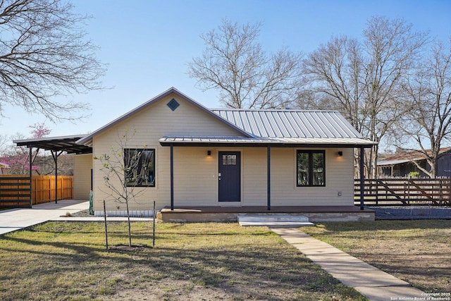 bungalow-style home with metal roof, fence, and a front lawn