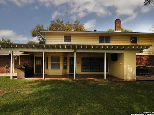 rear view of property with a patio area, a lawn, and a chimney