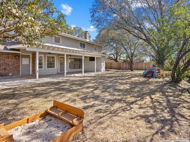 view of front of house featuring a patio, a ceiling fan, fence, a chimney, and a playground