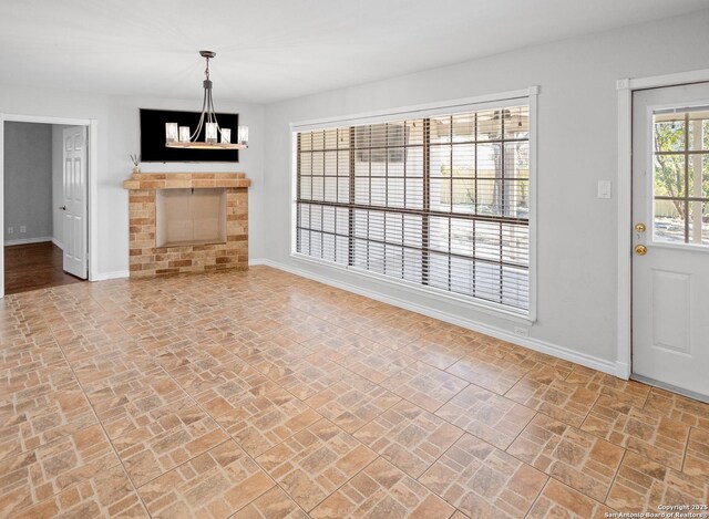 unfurnished living room featuring brick floor, a fireplace, and baseboards