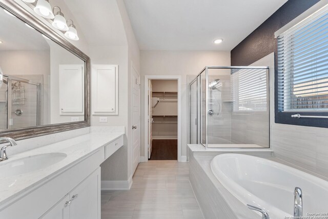 21950 Akin Byu, San Antonio, TX 78261 - bathroom with vanity, a stall shower, a walk in closet, a garden tub, and tile patterned floors
