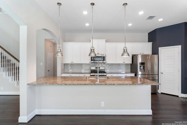 21950 Akin Byu, San Antonio, TX 78261 - kitchen featuring visible vents, arched walkways, stainless steel appliances, white cabinets, and backsplash