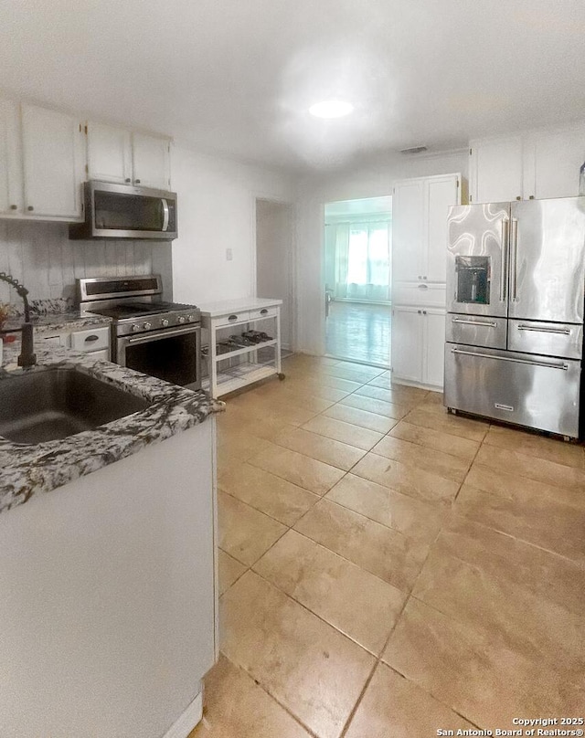231 Cicero, San Antonio, TX 78218 - kitchen with stainless steel appliances, a sink, white cabinets, decorative backsplash, and light tile patterned floors