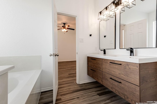 7519 Paraiso Hvn, Boerne, TX 78015 - bathroom featuring a tub to relax in, wood finished floors, double vanity, baseboards, and ceiling fan